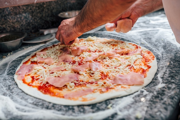 Ajout de salami sur la pizza. Fermer.