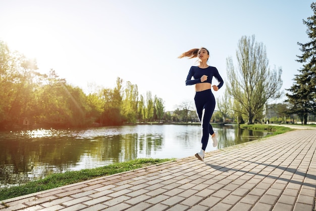 Ajustement sportif jeune femme jogging tôt le matin dans le parc