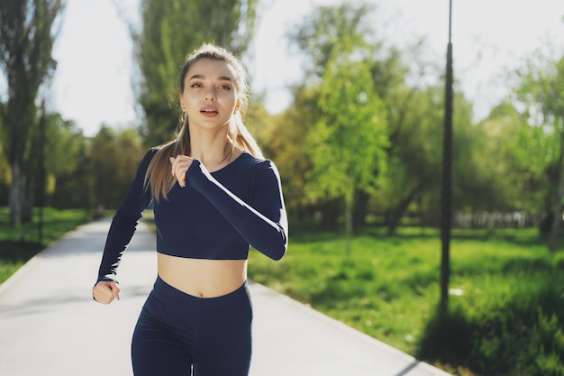 Ajustement sportif jeune femme jogging tôt le matin dans le parc