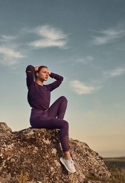 Ajuster la femme se reposant sur la colline rocheuse