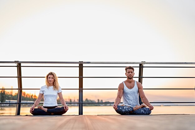 Ajuster le jeune couple faisant du yoga lotus pose des personnes de mode de vie sain activité sportive en plein air sur des vacances familiales ...