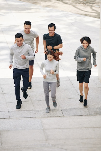 Ajuster les jeunes hommes et femmes vietnamiens souriants qui courent à l'extérieur lors de l'entraînement pour le marathon