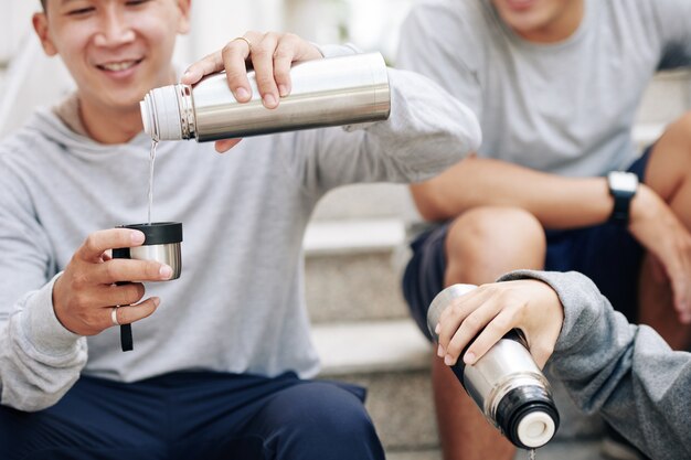 Ajuster les jeunes prenant des boissons vitaminées lorsqu'ils se reposent sur des marches après s'être entraînés à l'extérieur