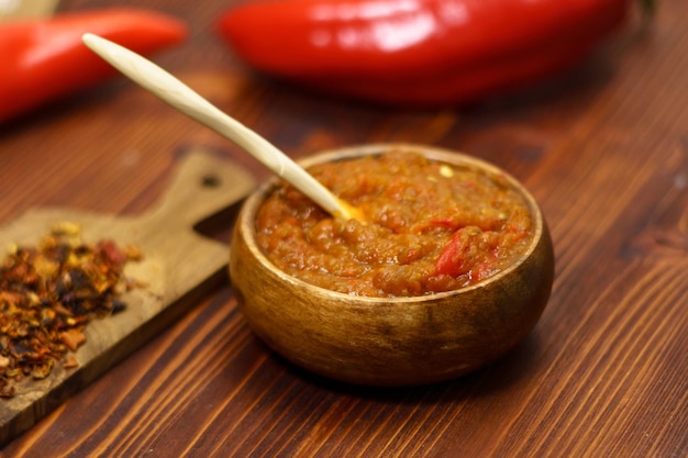 Ajvar à partir de paprika, de tomates, d'ail et d'oignons avec des épices sur une table en bois brun.