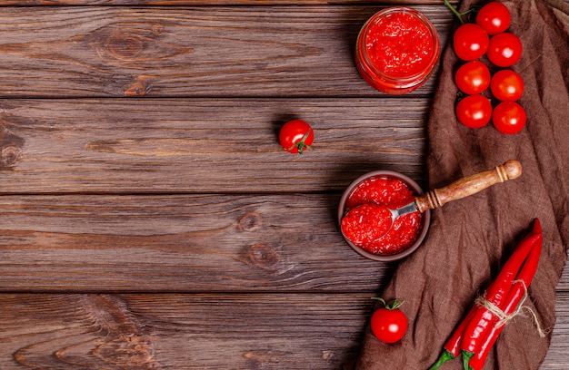 Ajvar ou pindjur tartinade de légumes rouges ou paprika au poivre et mousse de tomate dans un bol en argile sur une table en bois rustique.