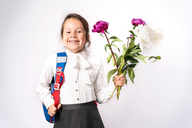 Al girl dans une chemise blanche tient des fleurs et un sac à dos