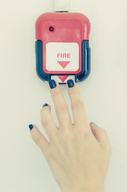 Alarme incendie La main d'une femme appuie sur un bouton d'alarme incendie