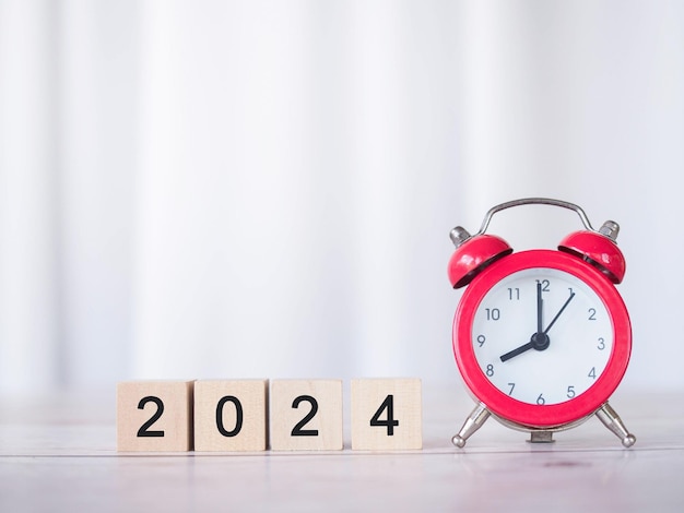 Alarme rouge et bloc en bois avec le numéro 2024 Le concept de gérer le temps pour le succès Investissement financier et affaires en croissance dans la nouvelle année 2024