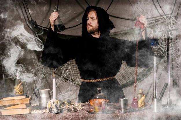 Photo l'alchimiste médiéval fait un rituel magique à table dans son laboratoire de fumée