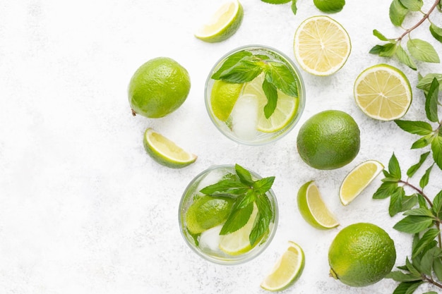 Alcool menthe cocktail mojito avec rhum et citron vert boisson froide d'été ou boisson avec jus de glace eau gazeuse sur table en pierre blanche avec espace de copie pour le texte Vue de dessus Mise à plat Gros plan