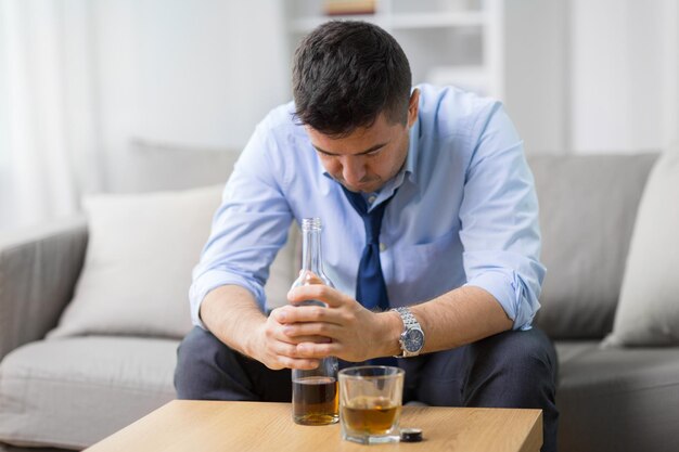 alcoolique avec une bouteille de whisky à la maison