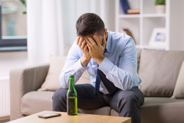 Photo alcoolique masculin avec une bouteille de bière à la maison