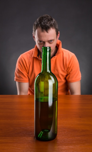 L'alcoolique regarde la bouteille de vin