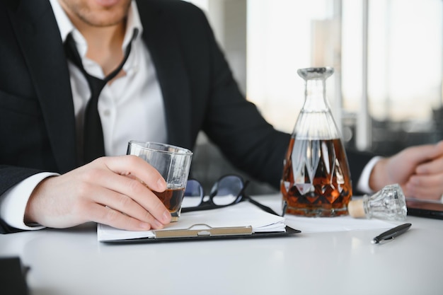 L'alcoolisme au travail Un employé fatigué qui boit de l'alcool sur le lieu de travail ne peut pas gérer le stress