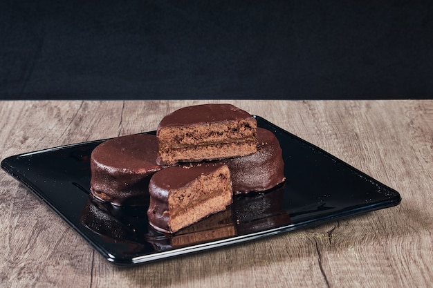 Alfajor au chocolat sur plaque noire sur une table en bois et fond sombre. Mise au point sélective. Copier l'espace