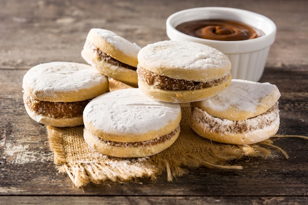 Alfajores argentines traditionnelles avec dulce de leche et sucre sur table en bois