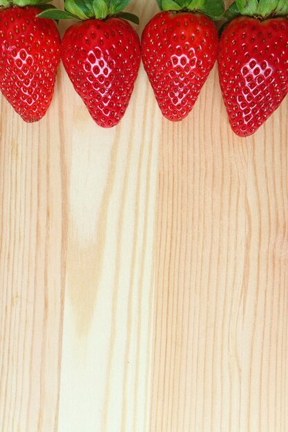 Photo alignés de fraises mûres fraîches sur une table en bois