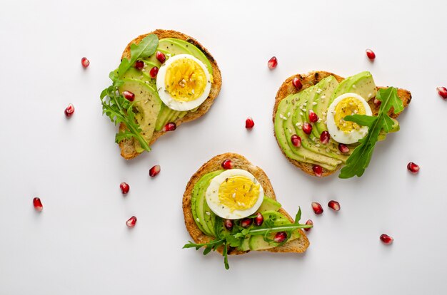 Alimentation équilibrée. Toasts à l'avocat avec des graines d'œuf, de roquette et de grenade. Vue de dessus, plat poser