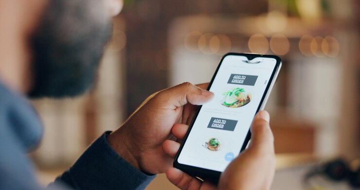 Photo l'alimentation en ligne et l'homme d'affaires avec un téléphone pour la livraison des commandes et le service d'application mobile au bureau menu du site web et personne sur l'écran du smartphone avec option pour le déjeuner, le dîner ou le repas en pause le soir