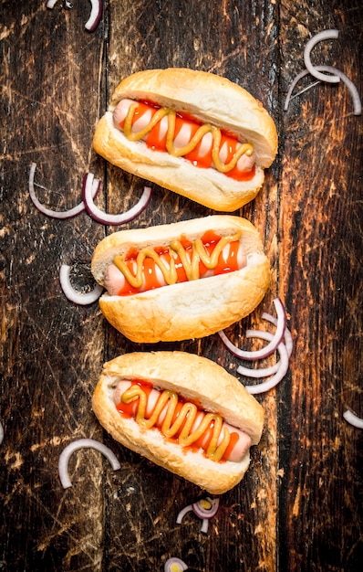 L'alimentation de rue. Hot-dogs à la moutarde et sauce tomate sur table en bois.