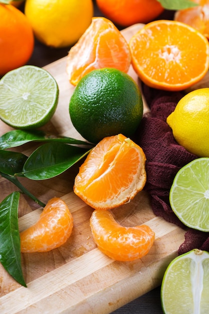 Alimentation saine alimentation nutrition nature concept Assortiment d'agrumes vitamine fond orange pamplemousse mandarine citron vert citron avec des feuilles sur une planche à découper en bois rustique