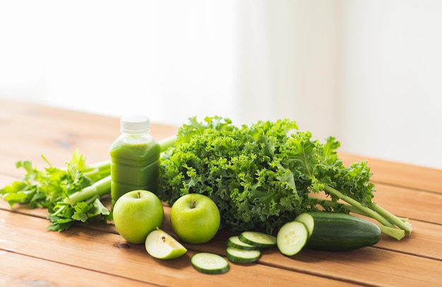 alimentation saine, alimentation, régime et concept végétarien - bouteille avec jus vert, fruits et légumes sur table en bois