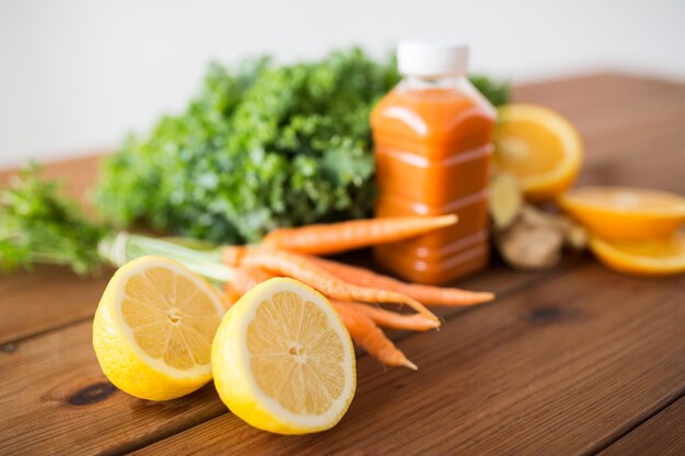 alimentation saine, alimentation, régime et concept végétarien - gros plan de citron et bouteille avec jus de carotte, fruits et légumes sur table en bois