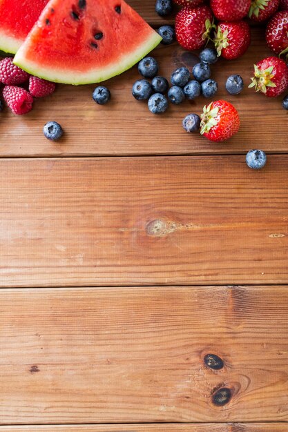 alimentation saine, alimentation, régime et concept végétarien - gros plan de framboise avec des tranches de fraise, de mûre et de pastèque sur une table en bois