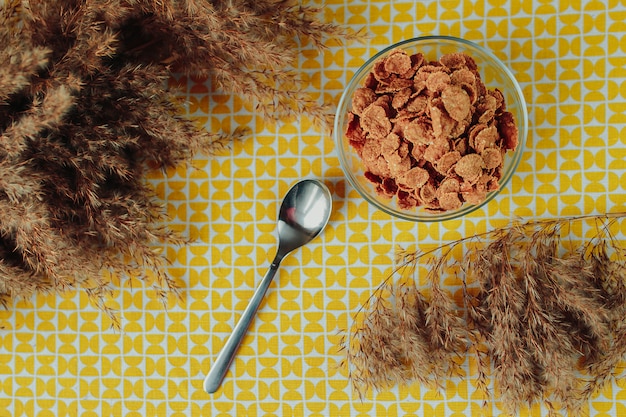 Une alimentation saine, des aliments sains sur la table, des céréales sombres dans le bol en verre, une cuillère et des fleurs séchées autour.