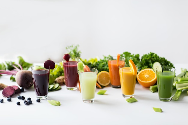 alimentation saine, boissons, régime alimentaire et concept de désintoxication - verres avec différents jus de fruits ou de légumes et aliments sur table