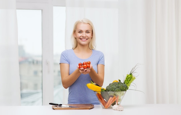 alimentation saine, cuisine, nourriture végétarienne, régime et concept de personnes - jeune femme souriante avec un bol de légumes à la maison