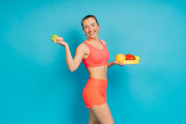 Une alimentation saine, une femme heureuse avec des fruits et légumes mange une pomme