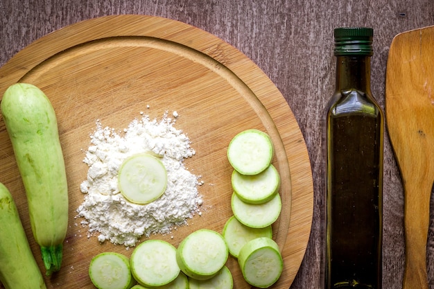 Alimentation saine, nourriture végétarienne. Courgettes crues préparées pour la friture dans une poêle avec des épices à l'huile d'olive. Vue de dessus. Fond en bois. Espace de copie. Nature morte. Mise à plat