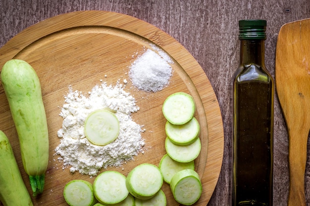 Alimentation saine, nourriture végétarienne. Courgettes crues préparées pour la friture dans une poêle avec des épices à l'huile d'olive. Vue de dessus. Fond en bois. Espace de copie. Nature morte. Mise à plat