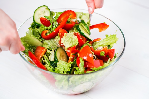 Alimentation saine, nourriture végétarienne, régime et concept de personnes - gros plan d'une jeune femme s'habillant d'une salade de légumes avec de l'huile d'olive sur fond blanc