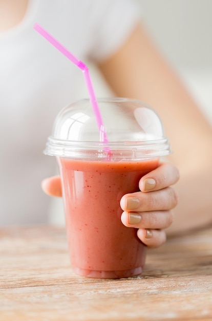 alimentation saine, régime alimentaire et concept humain - gros plan sur une femme tenant une tasse en plastique avec du jus ou un smoothie