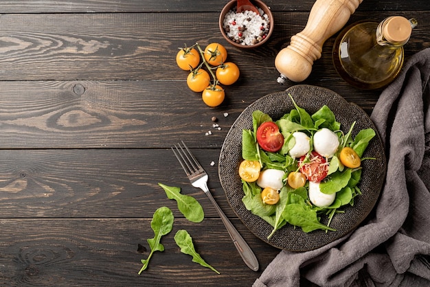 Alimentation saine et régime Salade fraîche avec roquette, tomates cerises, fromage mozzarella et fromage à pâte dure sur fond de bois foncé Vue de dessus