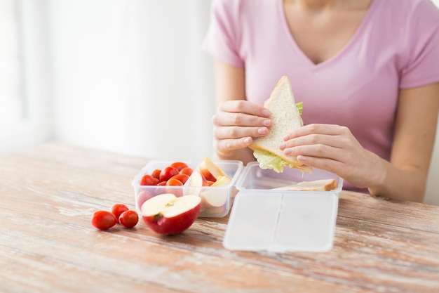 alimentation saine, stockage, régime et concept de personnes - gros plan d'une femme avec de la nourriture dans un récipient en plastique à la cuisine à domicile