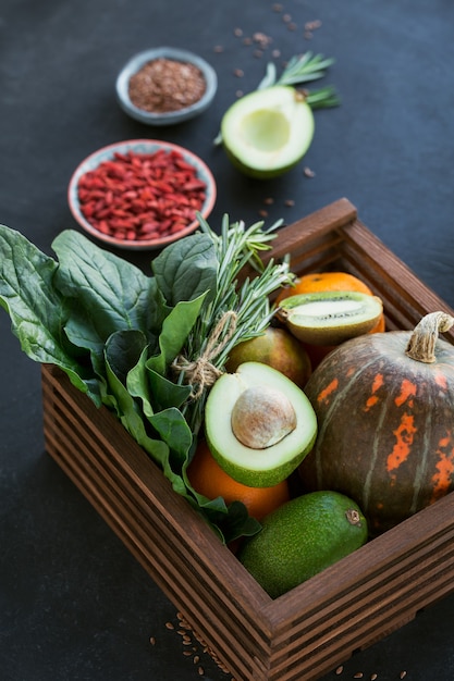 Aliments Biologiques Fermiers Sains Dans Une Boîte En Bois : Fruits, Légumes, Graines, Superaliments, Légumes-feuilles Sur Fond Noir. Concept De Sélection De Nourriture Propre