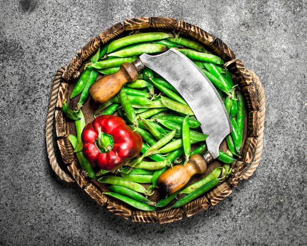 Aliments biologiques Pois verts au poivron et un vieux couteau sur un plateau sur un fond rustique