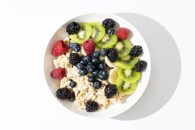 Aliments biologiques pour un petit-déjeuner sain et diététique. Vue de dessus du bol avec flocons d'avoine, kiwi frais, myrtille sur fond blanc. vue de dessus.