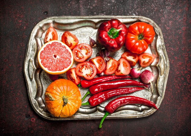 Aliments biologiques rouges Fruits et légumes frais sur un plateau en acier sur un fond rustique