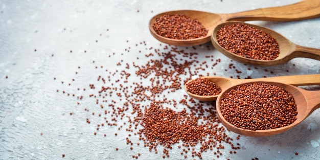 Aliments biologiques sains Quinoa brun sec dans une cuillère en bois Sur fond de pierre grise Vue de dessus