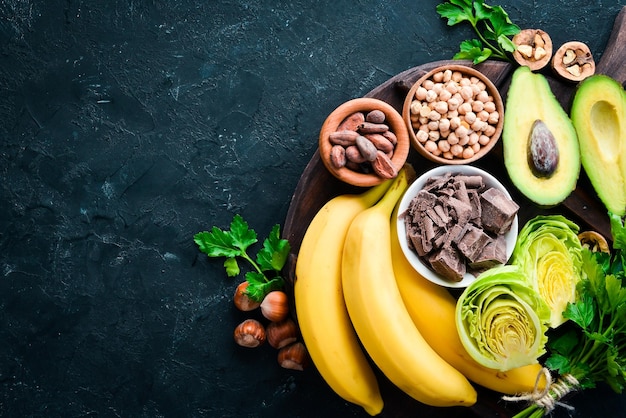 Aliments contenant du magnésium naturel Mg Chocolat Banane Noix de cacao Avocats Brocoli Amandes Vue de dessus Sur fond noir