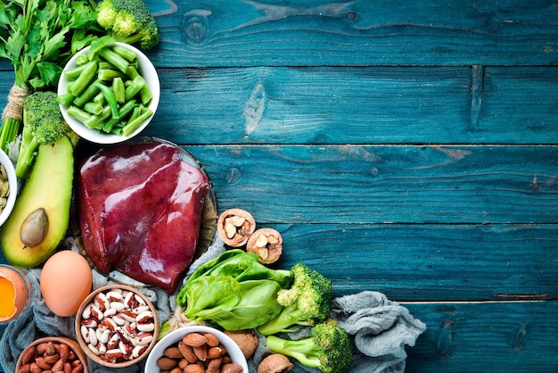 Aliments contenant de la vitamine B9 naturelle Foie avocat brocoli épinards persil haricots noix sur fond bleu Vue de dessus