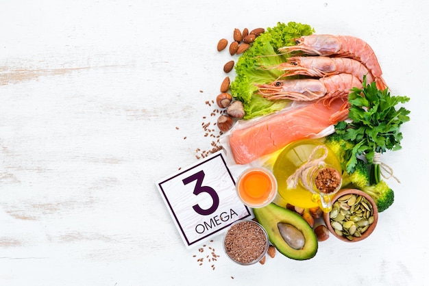 Aliments contenant de la vitamine oméga 3 Aliments sains avocats poisson crevettes brocoli noix de lin oeufs persil Vue de dessus Espace libre pour votre texte Sur un fond en bois blanc