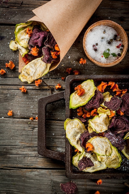 Aliments diététiques biologiques. Le régime végétalien. Légumes secs. Chips maison de betteraves, carottes et courgettes. Sur la vieille table rustique en bois, avec des légumes frais. vue de dessus du fond