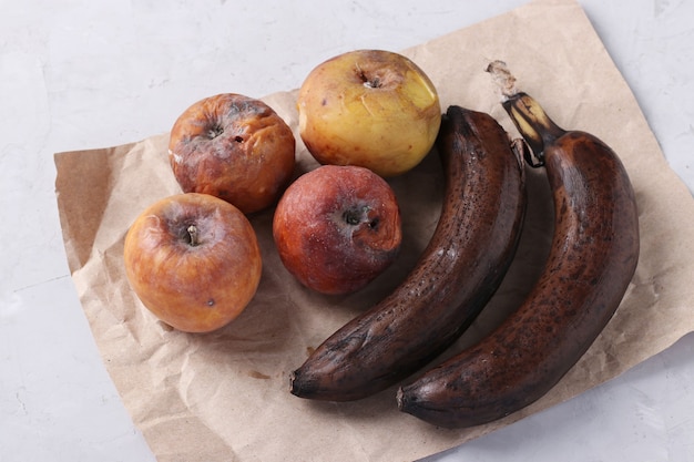 Aliments pourris gâtés avec moisissure : pommes et banane sur fond gris. Fermer.