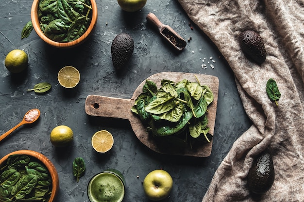 Aliments sains, cuisine et concept végétarien feuilles d'épinards frais, citron, pommes, avocat sur une planche à découper