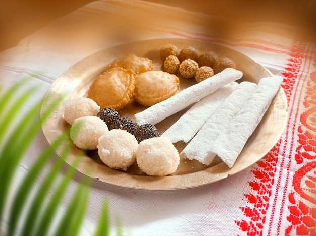 Des aliments traditionnels assames tels que le pitha laddu doi sira avec un fond de gamosa assamese
